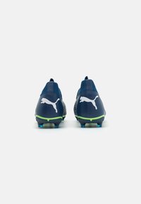 Botas de fútbol en color navy con un acabado texturizado, que presentan el logo de Puma en blanco, un acento verde en la suela y tacos azules para mayor tracción.