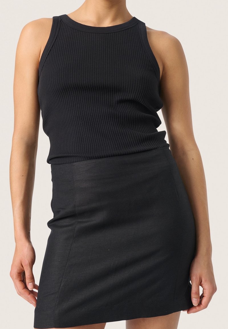 Top in tessuto a coste nero con scollatura rotonda abbinato a una gonna nera aderente, caratterizzata da una texture liscia e lunghezza sopra il ginocchio.
