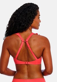 Koraalroze racerback bikini-top met verstelbare bandjes en haaksluiting. Gladde textuur, minimale naden en ergonomisch ontwerp voor een optimale pasvorm.