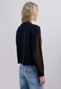Maglione corto blu navy con motivo a rombi marroni sulle maniche, orlo a coste e dettaglio con bottone sul retro. Texture a maglia morbida.
