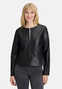 Svart faux läderjacka med peplumkjol, rund halsringning och framdragkedja. Långa ärmar med subtila sömnadsdetaljer.