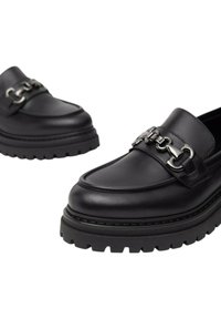 Mocassini in pelle nera con suola spessa, dettaglio in catena argentata sulla parte superiore, punta arrotondata e dettagli di cucitura in contrasto.