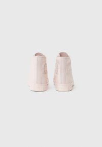 Rosa lerrets høye sneakers med et rundt logo-patch på den ytre hælen, teksturert overflate og gummisåle. Har sømmer langs siden.