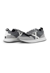 Des chaussures de sport grises avec un dessus en maille et des accents en daim, un logo blanc et des rayures contrastantes noires et blanches sur le talon.