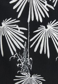 Černá látka s bílým květinovým vzorem, který obsahuje podlouhlé okvětní lístky a složité detaily vinné révy, čímž vytváří texturovaný vizuální efekt.