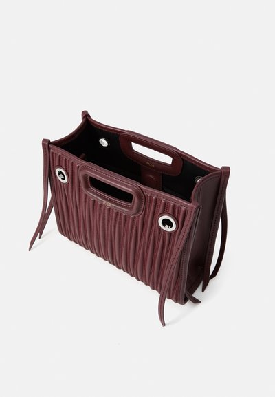 Bordeaux leren handtas met verticale ribbelstructuur, dubbele handvatten, zilveren hardwareaccenten en een open bovenkant. Binnenkant is zwart.