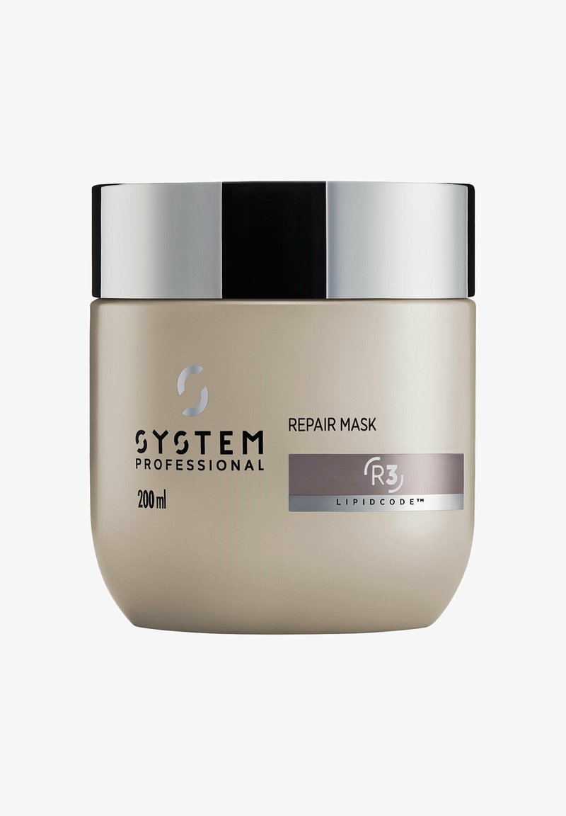 Reparaturmaske in einem 200 ml cremefarbenen Glas mit einem silbernen und schwarzen Metallverschluss. Auf der Vorderseite befinden sich der Markenname und Produktinformationen.