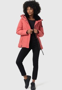 Coral puffer jacket with a faux fur-trimmed hood, zip closure, and side pockets. Worn with black fitted pants and black sneakers.