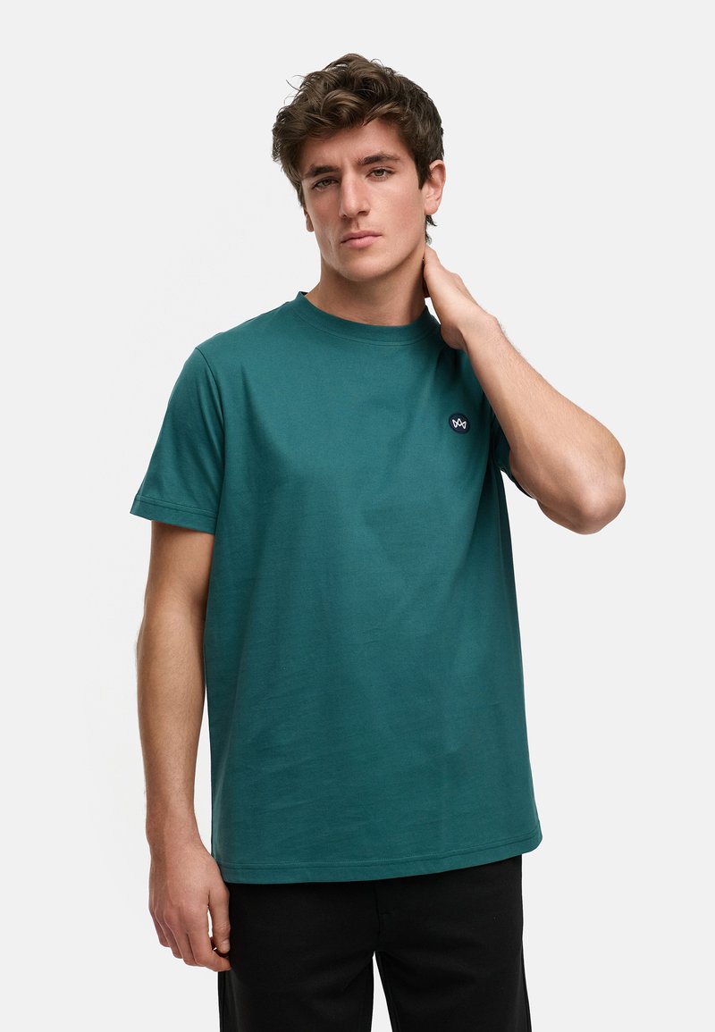 Teal bomull T-skjorte med korte ermer og rund hals, med en liten brodert logo på venstre bryst. Glatt tekstur, uformell passform.