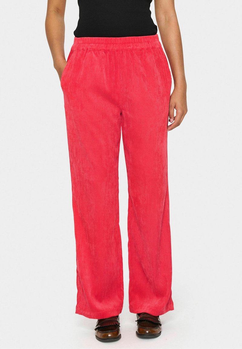 Pantalon large en velours côtelé rouge avec une taille élastique, doté de deux poches latérales et d'une texture douce. Design décontracté adapté à diverses tenues.