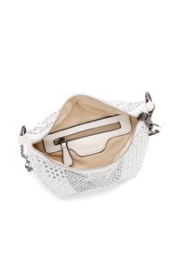 Bolso blanco con tachuelas metálicas, cierre de cremallera y cadena decorativa. El interior beige cuenta con un bolsillo con cremallera y una etiqueta con el logo.