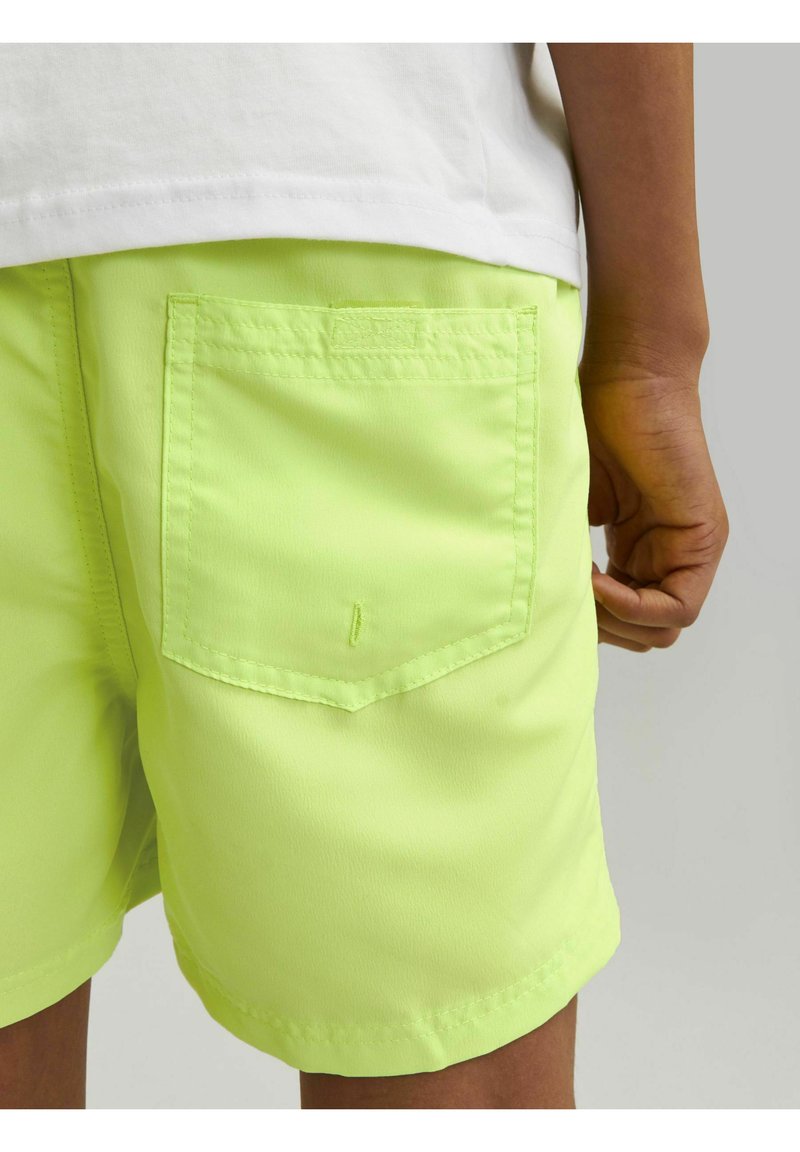 Pantalones cortos de color verde neón con una textura suave, que cuentan con un bolsillo trasero con una solapa rectangular y detalles de costura.