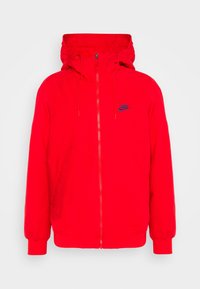 Röd Nike-hoodie med framsidans dragkedja, snörjusterbar huva, ribbad manschetter och sidofickor, uppvisad mot en vit bakgrund.