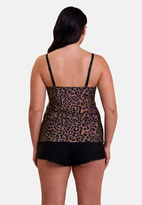 Haut de tankini à imprimé léopard avec des bretelles noires, associé à un short noir. Le matériau semble lisse et extensible, conçu pour la natation.