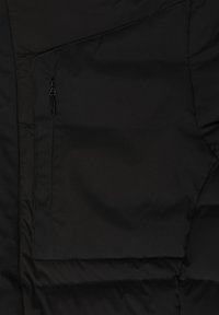 Sezione di giacca a vento nera con una texture liscia e opaca. Presenta una tasca con zip e cuciture a righe orizzontali. Design semplice e funzionale.