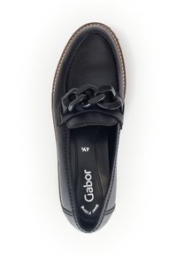 Black leather slip-on shoe featuring a braided accent on the vamp, rounded toe, and brown sole with contrasting stitching detail.