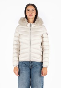 Giacca imbottita di un leggero color beige con cappuccio foderato in pelliccia e zip frontale; presenta un motivo a zig zag e polsini elastici.