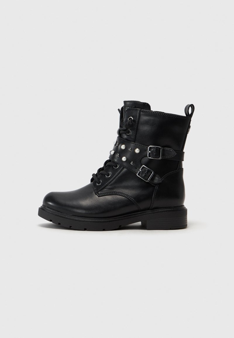 Botte de combat en cuir noir avec lacets sur le devant, deux sangles latérales avec boucles argentées, et des clous et perles argentés décoratifs sur les sangles.