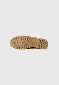 Brown rubber sole with a textured tread pattern, featuring ridges and star shapes for grip. Clear branding detail on the side.