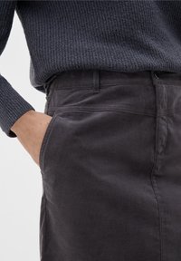 Pantalons en velours côtelé gris avec une texture lisse et une poche latérale. La ceinture comporte des passants de ceinture et une fermeture éclair.
