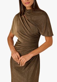 Abito bronzo metallizzato con un design in tessuto drappeggiato, maniche corte e arricciature laterali. La texture è liscia con una finitura luminosa.