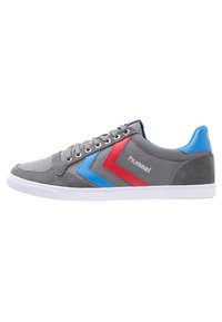 Gray sneaker with blue and red chevron accents, textured suede material, round toe, white rubber sole, and metal eyelets for laces.