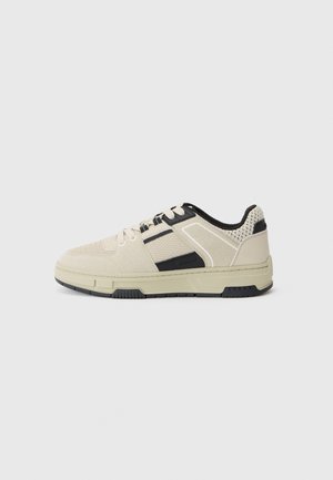 Beige sneakers with black accents, made of mesh and suede. Features a textured exterior, round toe, and flat rubber sole. Lace-up design.