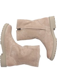 Botas de ante beige hasta la rodilla con superficie texturizada, cierre de cremallera lateral y suela de goma beige gruesa. Diseño de tacón plano y punta redonda.