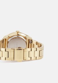 Gold stainless steel watch with a sleek, rounded case, a smooth metal bracelet, and a clasp engraved with the brand name "CLUSE."