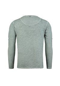 Camicetta a maniche lunghe di colore verde chiaro, realizzata in tessuto testurizzato, con scollatura a girocollo e un piccolo dettaglio con logo sulla manica.