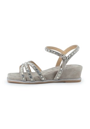 Wedge-Sandalen aus hellgrauem Wildleder, mit überkreuzten Riemen, die mit silbernen Nieten verziert sind, und einer glitzernden Sohle, ausgestattet mit einem verstellbaren Knöchelriemen.