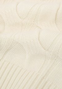 Suéter crema de punto grueso con un patrón de olas texturizado y dobladillo acanalado, confeccionado en una suave mezcla de lana.