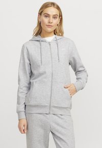Siva zip-up dukserica od mekane tkanine s kapuljačom na vezanje, prednjim džepovima, rebrastim manžetama i malim logotipom na prsima.