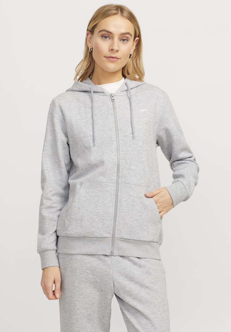 Siva zip-up dukserica od mekane tkanine s kapuljačom na vezanje, prednjim džepovima, rebrastim manžetama i malim logotipom na prsima.