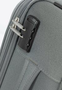 Graue Hartschalen-Kofferecke mit Reißverschluss, ausgestattet mit einem schwarzen Zahlenschloss, silbernen Reißverschlussanhängern und strukturiertem Stoff.