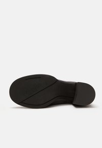Suola nera di stivale caratterizzata da una texture liscia, una leggera curva e un dettaglio di marchio. Include scanalature ben definite per una buona aderenza e una forma della punta arrotondata.