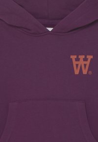 Sudadera morada hecha de una suave mezcla de algodón, con un bolsillo frontal y un logo 'W' naranja en el pecho. Diseño clásico de tipo pullover con puños acanalados.