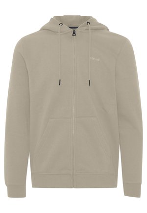 Hanorac crem cu fermoar, realizat dintr-un material moale, având glugă reglabilă cu șnururi, buzunare frontale spațioase și un detaliu discret cu logo pe piept.