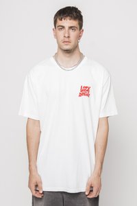 T-shirt bianca in cotone con una vestibilità ampia, che presenta un testo grafico rosso "LAZY" e "ANYTHING" sul lato sinistro del petto. Maniche corte, design con collo rotondo.