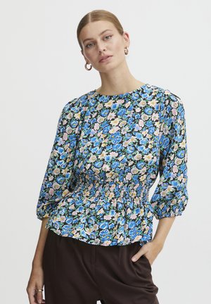 Bloes met bloemenpatroon met een gerimpelde taille, driekwart mouwen en een ronde hals. De stof heeft levendige blauwe, roze en groene bloemen op een zwarte achtergrond.