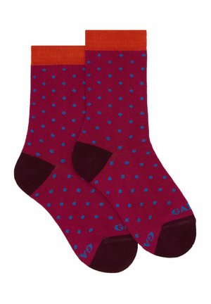Calzini color bordeaux con polsini a coste arancioni, caratterizzati da pois blu su tutta la superficie. Accentuati da talloni e punte di un bordeaux scuro.