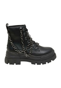 Botte de combat en cuir noir avec une semelle épaisse à crampons et une décoration en chaîne argentée drapée sur le côté et la zone des lacets à l'avant.