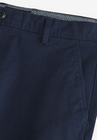 Pantalones azul marino elaborados con una tela suave, que cuentan con un bolsillo frontal, pasadores para el cinturón y un forro de cintura con un patrón.