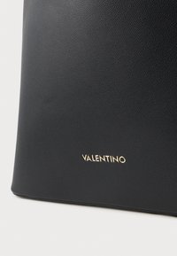 Black textured leather bag with a sleek rectangular shape. Gold "Valentino" logo featured prominently at the bottom.