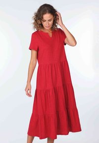 Rotes schichted Kleid mit kurzen Ärmeln, V-Ausschnitt und weichem Textil. Fließende Silhouette mit gerafften Schichten am Saum.