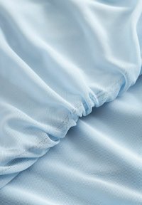 Tissu en maille bleu clair avec une texture fine et aérienne, présentant des sections froncées créant des volants subtils et une apparence lisse et fluide.