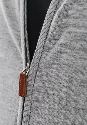 Szary dziergany kardigan zapinany na zamek z teksturowanej tkaniny, z metalowym zamkiem błyskawicznym i skórzaną pętelką w kolorze brązowym. Dopasowany dekolt, bez wzoru.