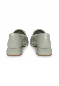 Lichtgroene gepatineerde leren loafers met een gladde textuur, afgeronde achterkant en een lage, stevige tan zool. Minimalistisch ontwerp, geen zichtbare hardware.
