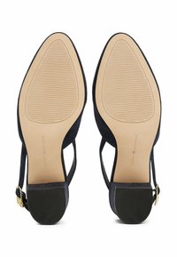 Chaussures à talons hauts en daim bleu marine avec un dos ouvert, un bout pointu et une semelle en caoutchouc dotée de rainures horizontales pour une meilleure traction. Détail en boucle dorée.