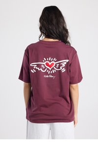 T-shirt en coton bordeaux à manches courtes. Le dos présente un motif de cœur ailé blanc avec des accents rouges. Le nom de la marque "Kids Hani" est imprimé en dessous.
